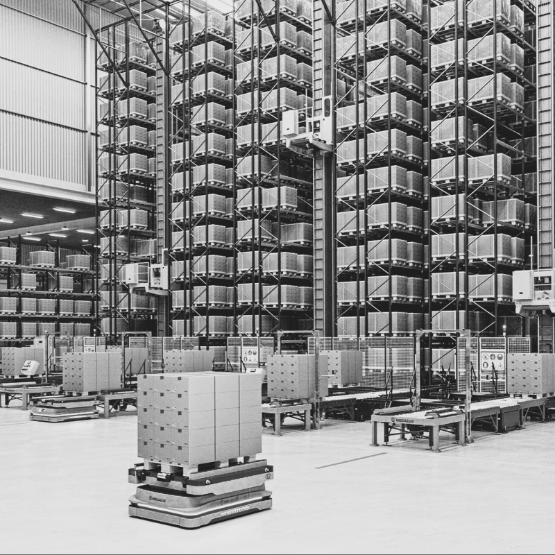 Interior of a spacious industrial warehouse with stacked shelving and logistical infrastructure.